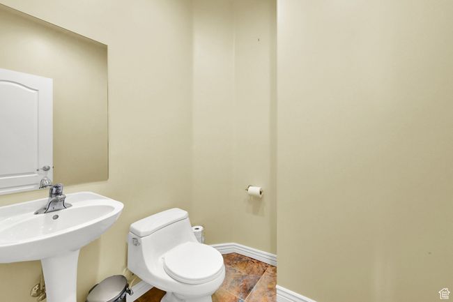 Bathroom featuring a sink, toilet, baseboards, and stone tile flooring | Image 39