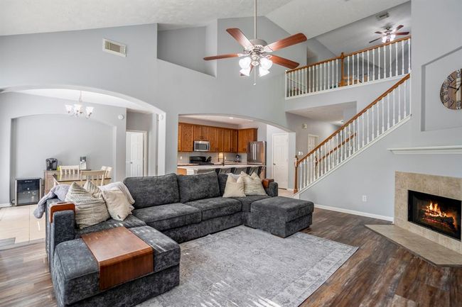 From this angle near the back windows, you’ll appreciate the grand two-story vaulted ceilings, recessed architectural details, and large arched openings that connect the living room to the breakfast area and kitchen—creating an open, elegant flow throughout the heart of the home. | Image 8