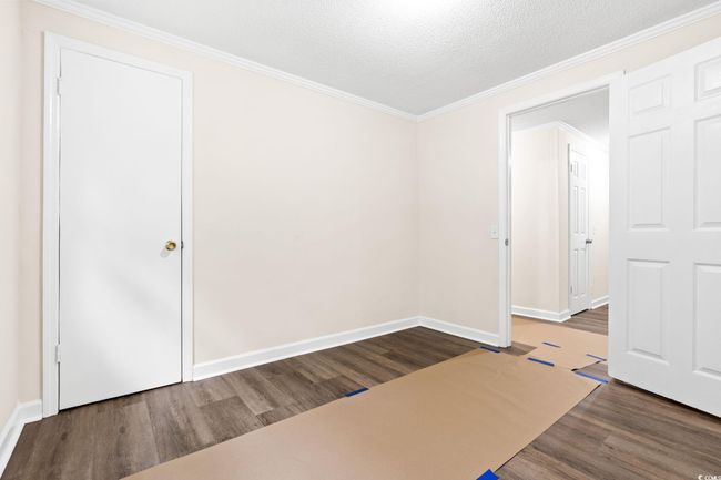 Unfurnished room with wood finished floors, crown molding, baseboards, and a textured ceiling | Image 35