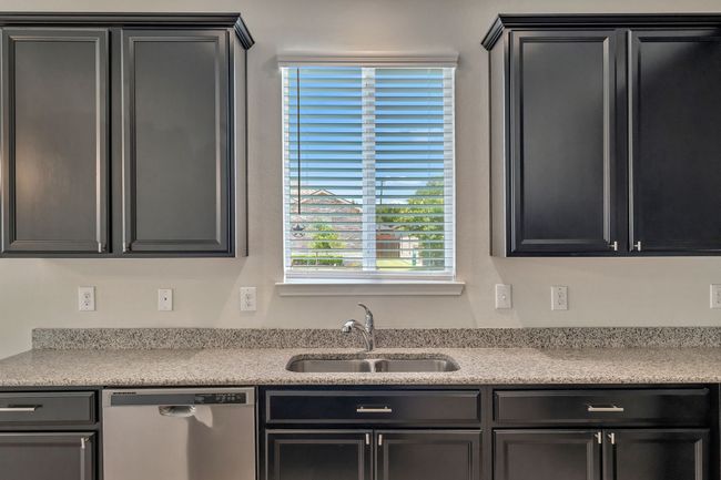 Kitchen with stainless steel dishwasher, light countertops, and dark cabinetry | Image 11