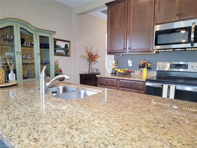 Kitchen with light stone countertops, stainless steel appliances, and a sink | Image 15