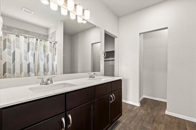 Full bath with wood finished floors, double vanity, baseboards, and curtained shower | Image 18