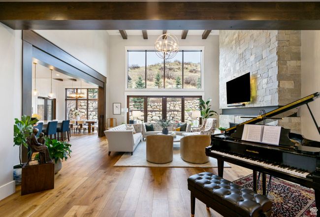 Living room featuring wood-type flooring, a high ceiling, beam ceiling, and a chandelier | Image 19