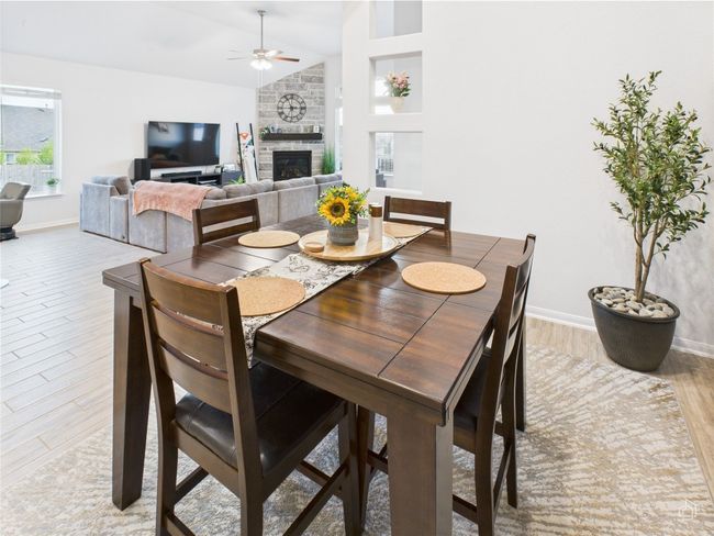 Dining area featuring ceiling fan, baseboards, a fireplace, light wood-style flooring, and vaulted ceiling | Image 14