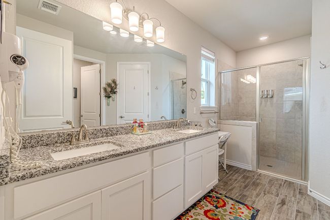 Bathroom featuring a shower stall, double vanity, and wood finished floors | Image 18