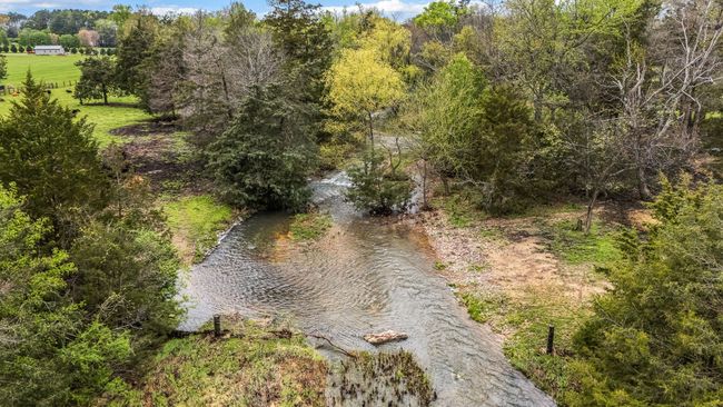 Nestled in the picturesque landscape of Decherd, Tennessee, this charming mini farm boasts a delightful creek that winds its way through the property, adding a serene and enchanting quality to the land. | Image 23