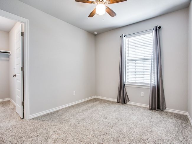 Unfurnished bedroom with carpet floors, a spacious closet, baseboards, and ceiling fan | Image 13
