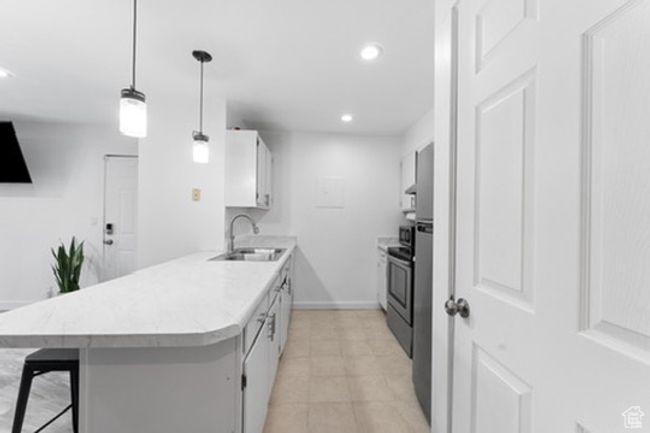 Kitchen featuring a kitchen breakfast bar, light countertops, a peninsula, recessed lighting, and white cabinetry | Image 4