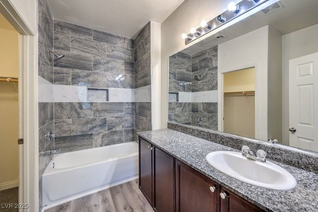 Bathroom with visible vents, wood finished floors, vanity, shower / washtub combination, and a spacious closet | Image 5