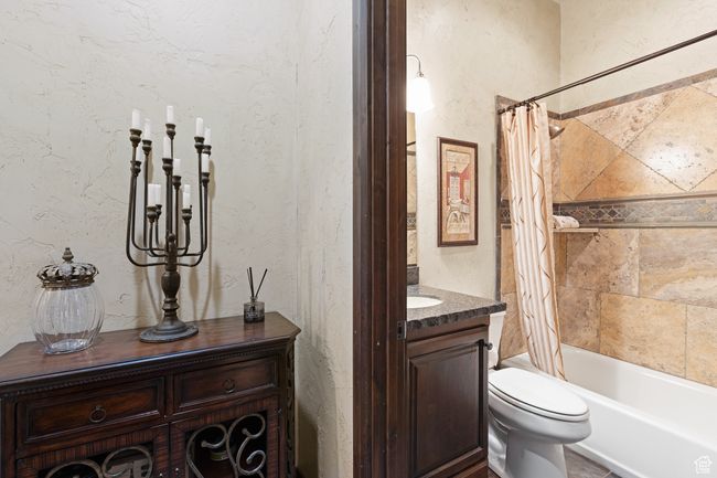Full bath featuring vanity, shower / bathtub combination with curtain, and a textured wall | Image 42