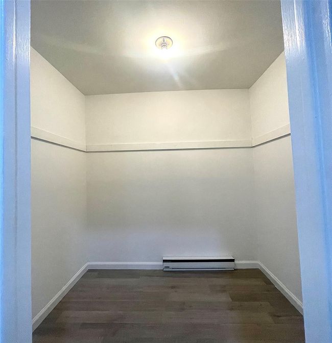 Walk in closet featuring dark wood-style flooring and baseboard heating | Image 48