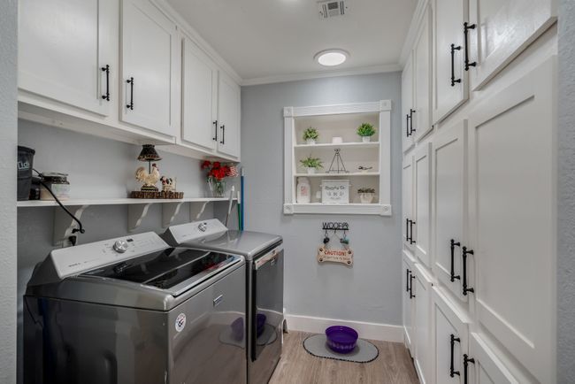 Laundry room featuring washer and dryer, cabinet space, light wood finished floors, and ornamental molding | Image 15