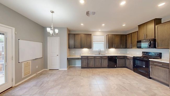 Kitchen featuring visible vents, a healthy amount of sunlight, a sink, and black appliances | Image 14