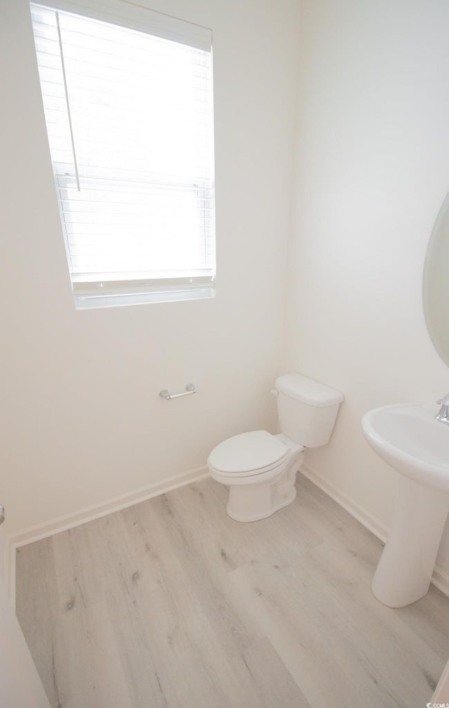 Half bathroom with wood finished floors, baseboards, and toilet | Image 7