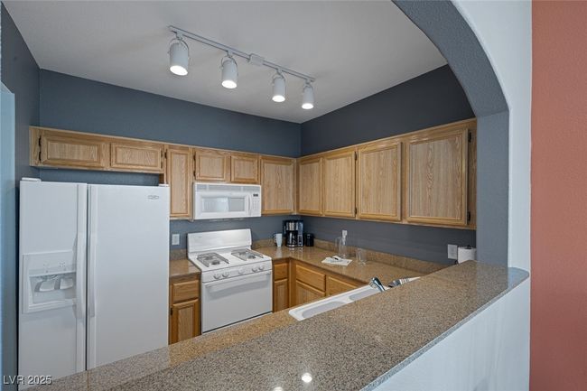 Kitchen featuring a sink, arched walkways, and white appliances | Image 11