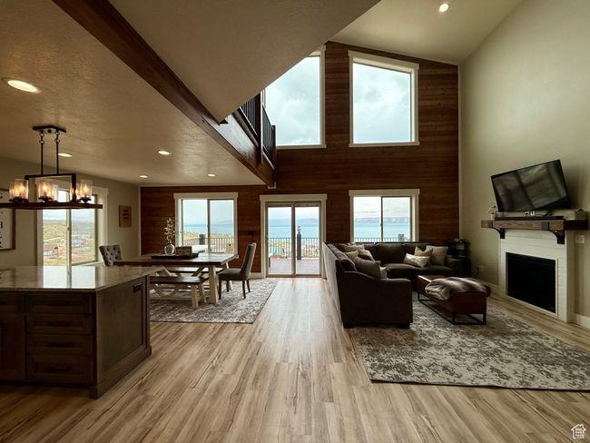Living room with a fireplace, wood walls, a notable chandelier, recessed lighting, and light wood-style flooring | Image 16