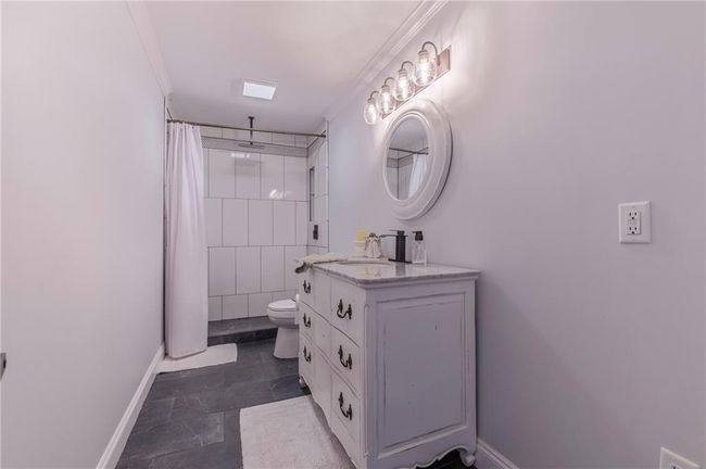 Bathroom with a shower with shower curtain, vanity, toilet, and ornamental molding | Image 22