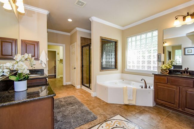 Finished with elegant tiling, the primary bathroom features dual vanities, a soaking tub, and a separate glass-enclosed shower. The thoughtful layout and details offer everyday luxury. | Image 24
