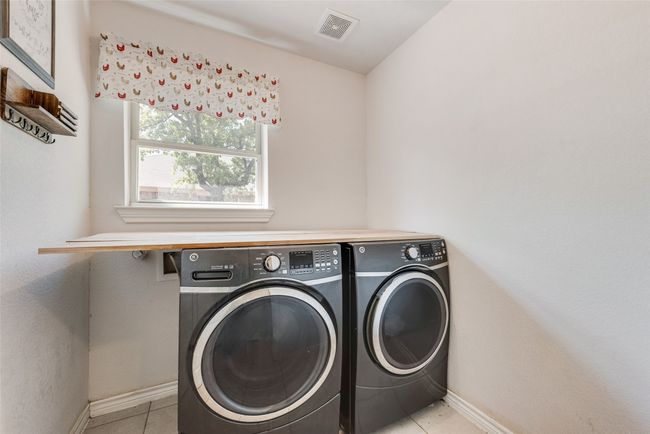 Laundry area featuring visible vents, baseboards, light tile patterned floors, washer and dryer, and laundry area | Image 27
