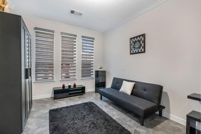 This room features a modern, minimalist design. Ample natural light streams through three large windows, complemented by neutral walls and contemporary decor, creating a cozy yet sophisticated ambience. | Image 8