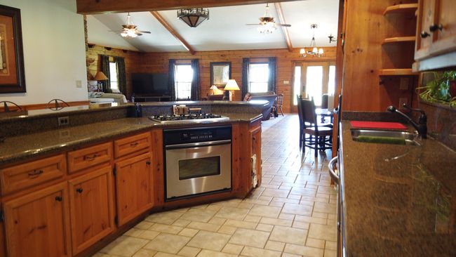 Kitchen featuring stainless steel appliances, open floor plan, ceiling fan with notable chandelier, and a sink | Image 12