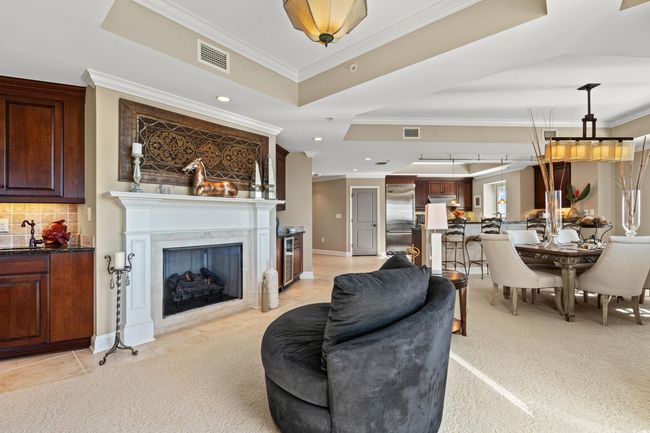 Living area featuring a tray ceiling, ornamental molding, a fireplace, recessed lighting, and beverage cooler | Image 6