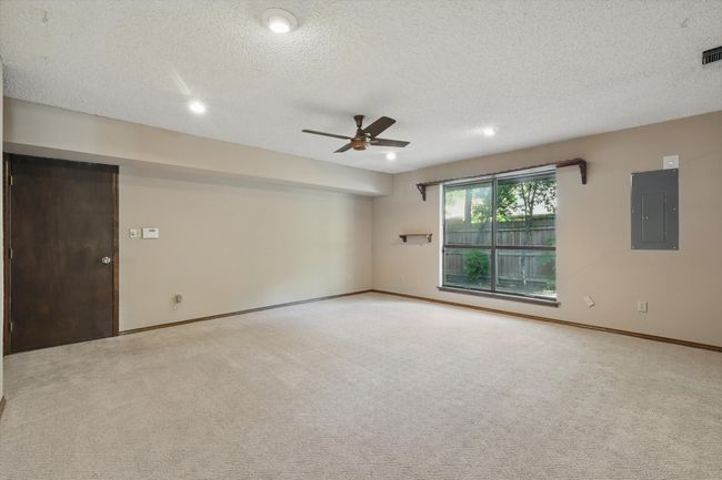 Empty room featuring electric panel, a textured ceiling, baseboards, ceiling fan, and carpet floors | Image 12