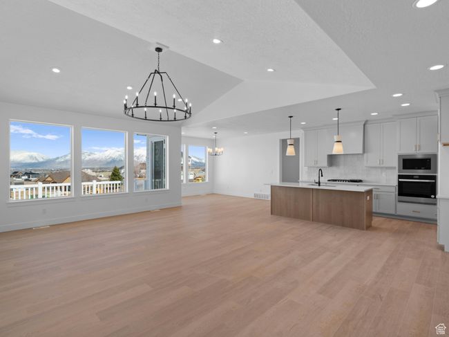 Kitchen with light countertops, open floor plan, light wood-style flooring, stainless steel appliances, and an inviting chandelier | Image 7