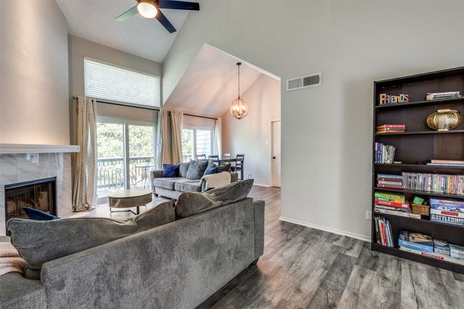 Living room with high vaulted ceiling, ceiling fan, wood finished floors, a chandelier, and a high end fireplace | Image 14