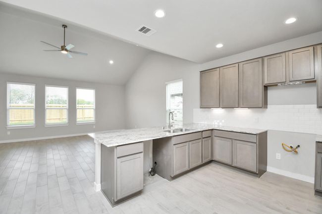 The open concept effortlessly connects the kitchen to the expansive family room, forming a perfect hub for gatherings. This seamless flow creates an inviting space where cooking and socializing come together harmoniously. | Image 16