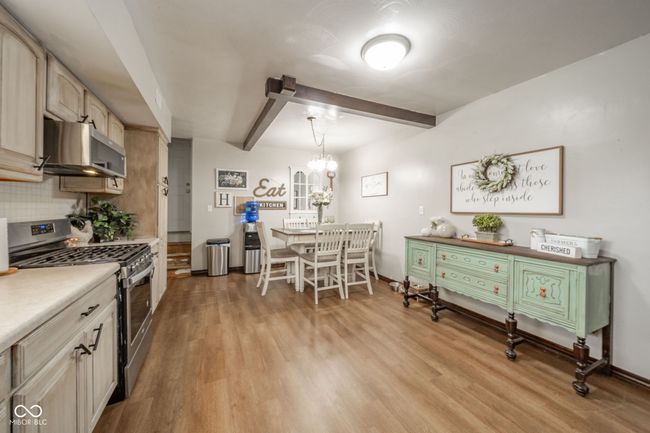 kitchen featuring tasteful backsplash, exhaust hood, light wood-style floors, beam ceiling, and stainless steel range with gas stovetop | Image 32