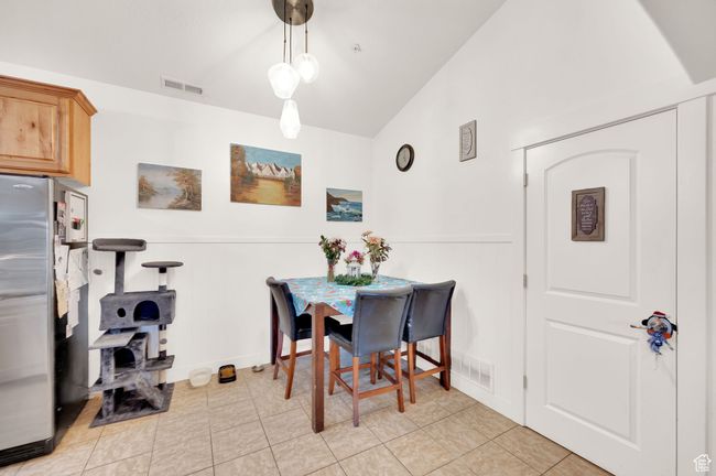 Dining space featuring vaulted ceiling, a wainscoted wall, and light tile patterned floors | Image 5