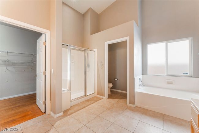 Full bath featuring high vaulted ceiling, a shower stall, toilet, tile patterned floors, and a garden tub | Image 32