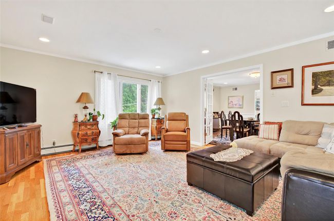 Living area with light wood-style flooring, crown molding, baseboard heating, and recessed lighting | Image 14