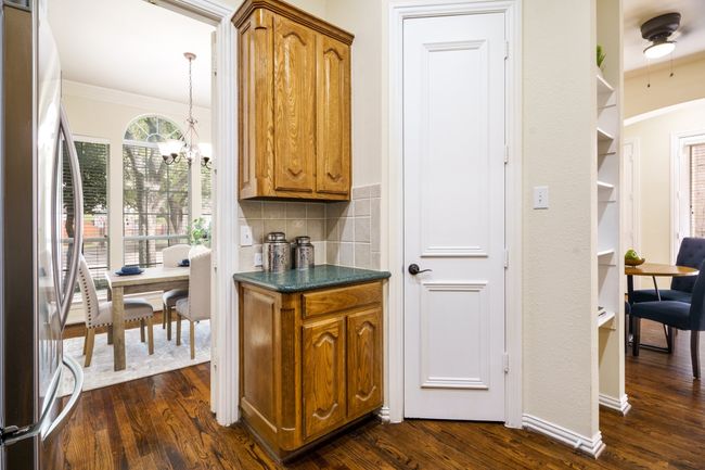 Kitchen with backsplash, freestanding refrigerator, cabinets, granite countertops, and wood flooring | Image 6