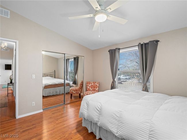 Bedroom featuring visible vents, wood finished floors, a closet, lofted ceiling, and ceiling fan | Image 43