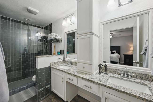 Ensuite bathroom featuring double vanity, a shower stall, ceiling fan, a textured ceiling, and wood finished floors | Image 26