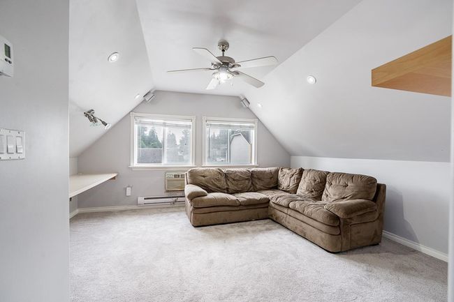 Living area with lofted ceiling, a baseboard heating unit, baseboards, carpet floors, and ceiling fan | Image 27