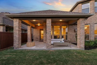 Back house at dusk featuring a patio and a lawn | Image 2