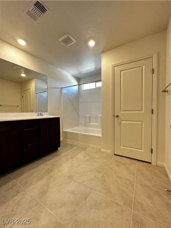 Bathroom featuring tile patterned flooring, visible vents, a textured ceiling, and vanity | Image 7