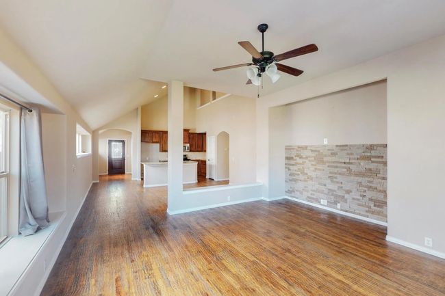 Unfurnished living room with arched walkways, a ceiling fan, wood finished floors, and high vaulted ceiling | Image 16
