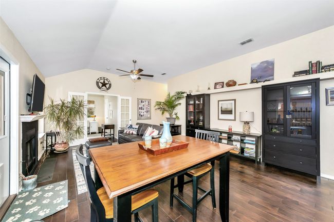 Dining area with lofted ceiling, ceiling fan, dark wood finished floors, and a fireplace with flush hearth | Image 9