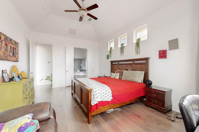 Bedroom with visible vents, high vaulted ceiling, connected bathroom, and wood finished floors | Image 14