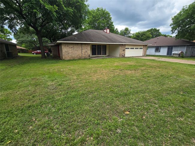 View of front of home with concrete driveway, a garage, a front lawn, a chimney, and brick siding | Image 22