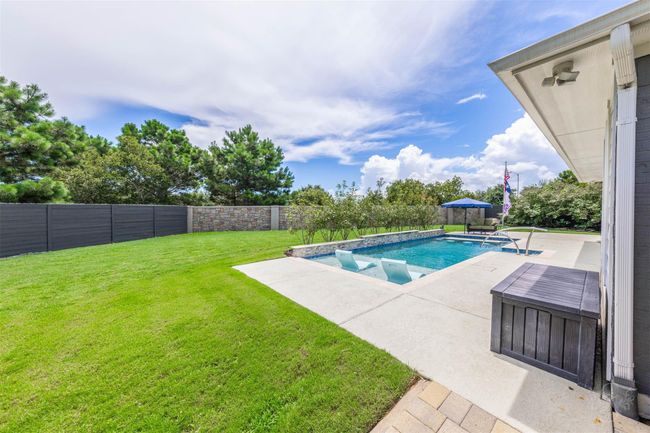 The backyard features a refreshing pool alongside lush green space, creating a perfect blend of leisure and nature. The verdant lawn complements the pool area, offering a serene and inviting outdoor retreat. | Image 36