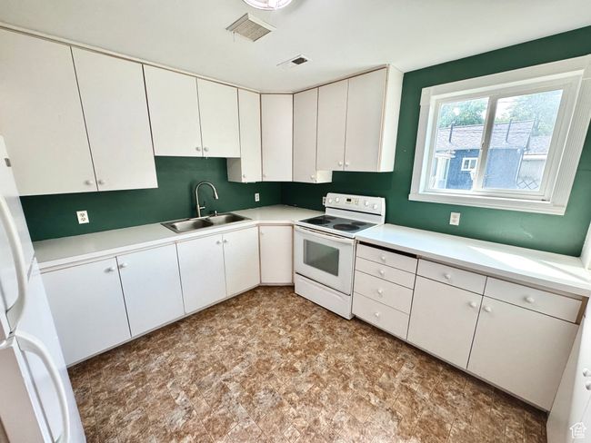 Kitchen with light countertops, a sink, white appliances, and white cabinets | Image 24