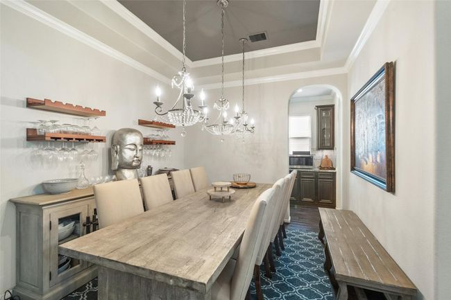 This elegant dining room features a stylish chandelier, and decorative shelving for glassware. The room has a contemporary feel with neutral tones, crown molding, and an adjacent butler's pantry for added convenience. | Image 15