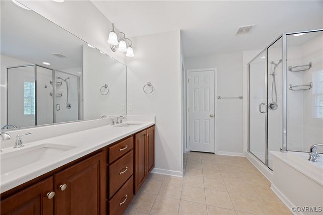 Full bathroom featuring visible vents, a shower stall, tile patterned flooring, double vanity, and water closet | Image 39
