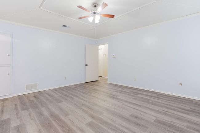 Unfurnished room featuring ceiling fan, visible vents, ornamental molding, and light wood finished floors | Image 16