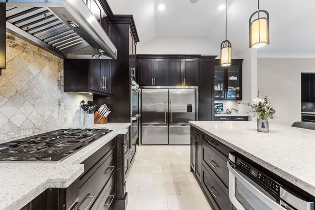 Kitchen with decorative backsplash, ornamental molding, light stone countertops, stainless steel appliances, and ventilation hood | Image 13